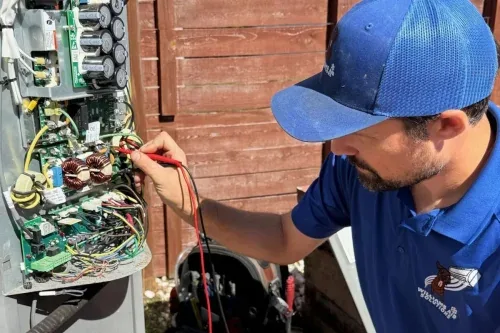 Williams Air Solutions technician testing an outdoor AC unit circuit board with a multimeter in Belleair, Florida