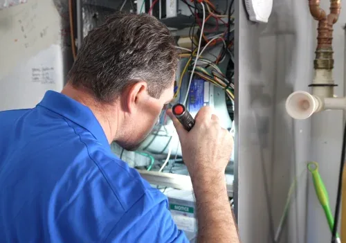 Williams Air Solutions technician inspecting an air handler with a flashlight during an AC repair in Pinellas County