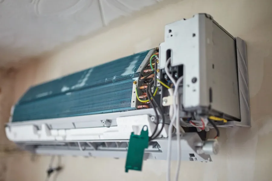 Interior of a wall-mounted mini split head unit showing the evaporator coil and refrigerant lines during service